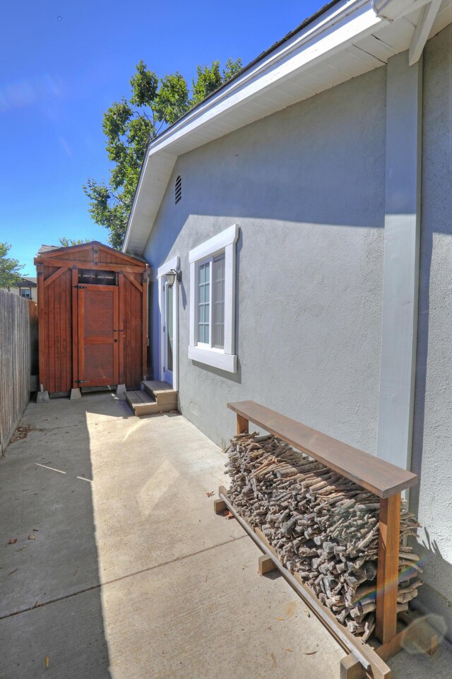 view of side of home featuring a storage unit and a patio