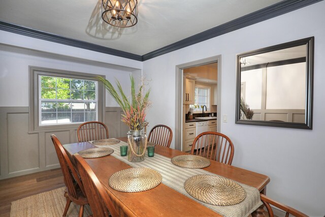 dining room featuring hardwood / wood-style flooring, an inviting chandelier, sink, and ornamental molding