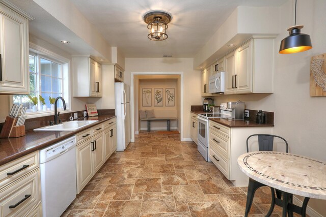 kitchen with sink, hanging light fixtures, light tile patterned flooring, and white appliances