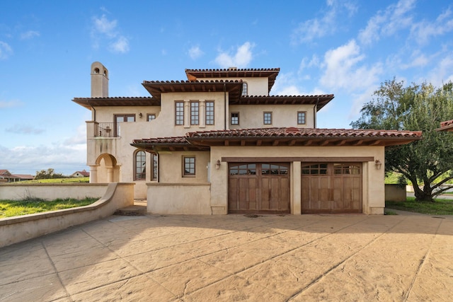 view of front of property with a balcony, driveway, and a chimney