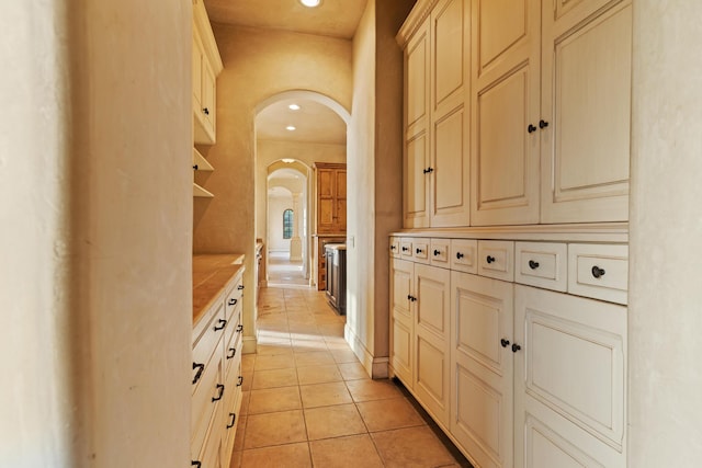 hall with arched walkways, recessed lighting, and light tile patterned floors