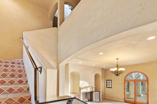 interior details with arched walkways, recessed lighting, a notable chandelier, baseboards, and a lit fireplace