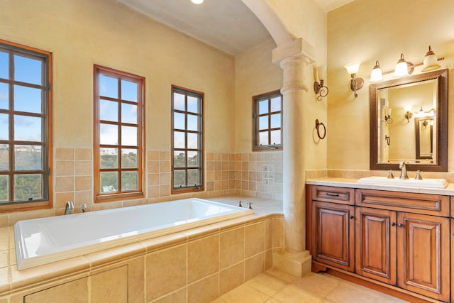 full bath featuring tile patterned flooring, a garden tub, vanity, and ornate columns