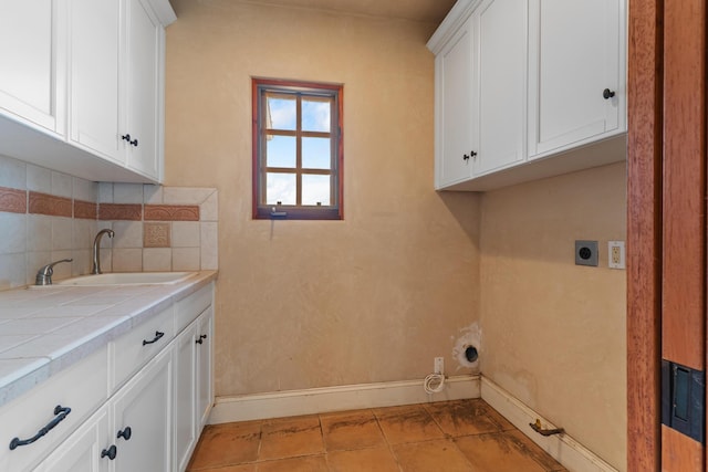 laundry room featuring cabinet space, baseboards, gas dryer hookup, electric dryer hookup, and a sink