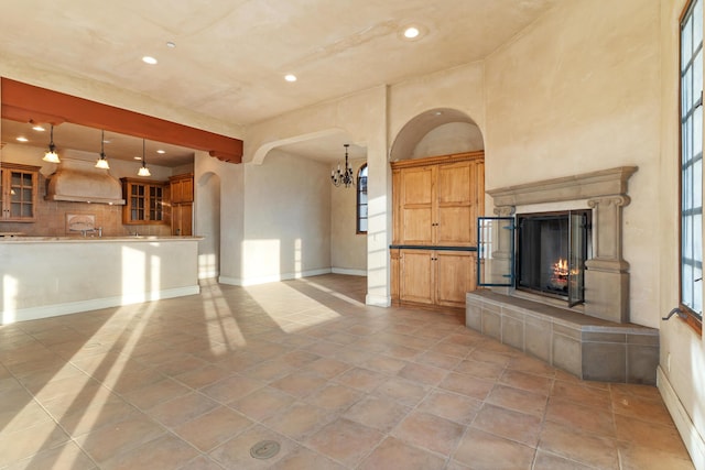 unfurnished living room featuring recessed lighting, baseboards, arched walkways, and a tile fireplace