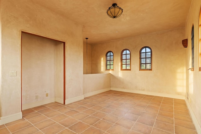 empty room with tile patterned flooring and baseboards