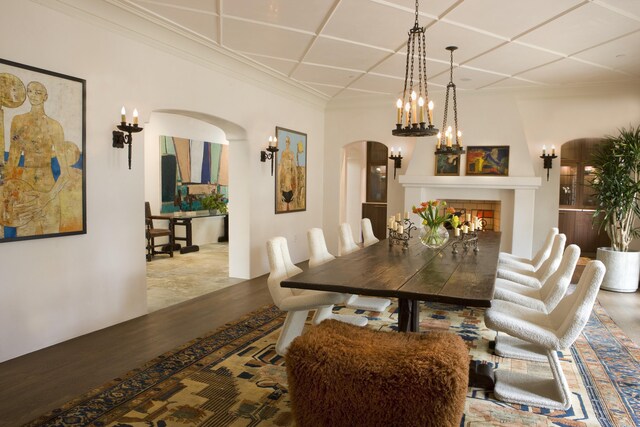 dining space with hardwood / wood-style flooring, coffered ceiling, and a tiled fireplace