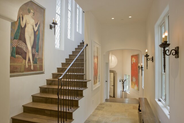 stairs featuring tile patterned floors, plenty of natural light, and a towering ceiling