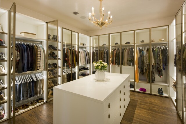 spacious closet featuring an inviting chandelier and dark hardwood / wood-style floors