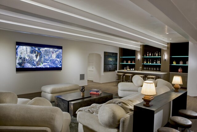 living room featuring built in features, indoor bar, beamed ceiling, and hardwood / wood-style floors