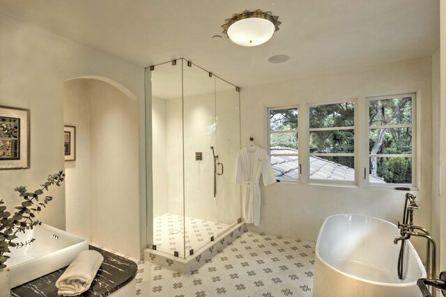 bathroom with a wealth of natural light, shower with separate bathtub, sink, and tile patterned floors