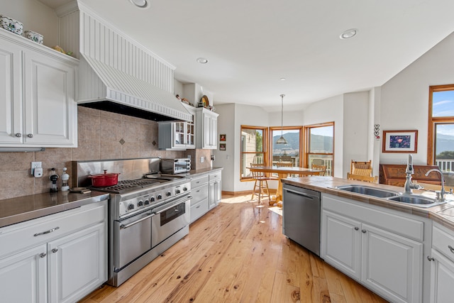 kitchen featuring light hardwood / wood-style flooring, premium range hood, sink, appliances with stainless steel finishes, and white cabinets