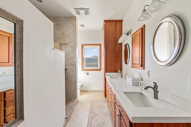 bathroom with tile patterned flooring, vanity, toilet, and tiled shower