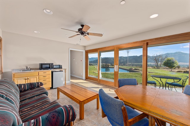 living room with ceiling fan, a water and mountain view, and sink