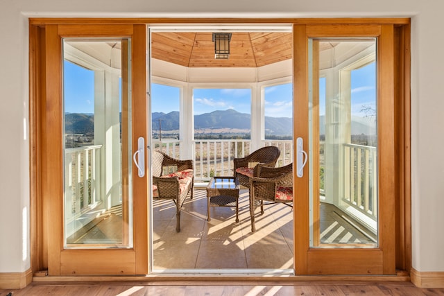 doorway featuring a mountain view, lofted ceiling, wooden ceiling, and light hardwood / wood-style floors