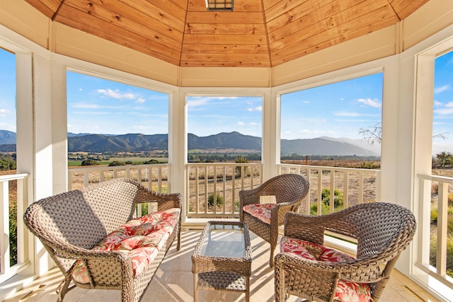 sunroom / solarium with lofted ceiling, a mountain view, and wood ceiling