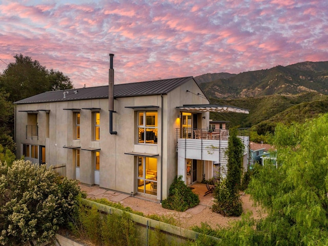 back house at dusk with a mountain view and a balcony