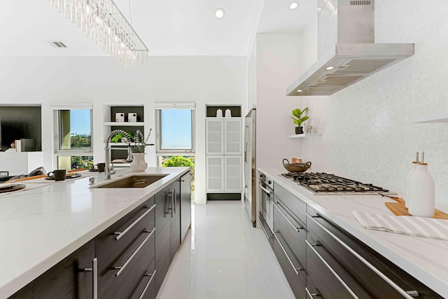 kitchen featuring light stone counters, appliances with stainless steel finishes, decorative light fixtures, sink, and wall chimney exhaust hood