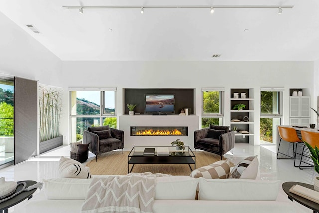 living room with a high ceiling, plenty of natural light, and track lighting