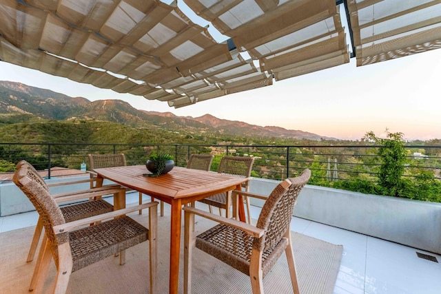 balcony at dusk featuring a patio, a pergola, and a mountain view