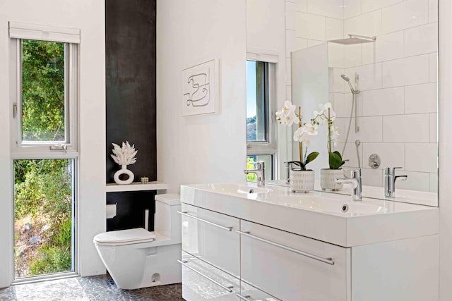 bathroom featuring toilet, vanity, and a tile shower