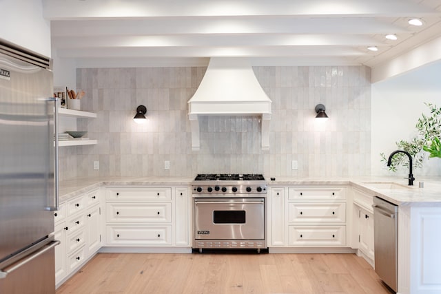 kitchen featuring high quality appliances, light hardwood / wood-style flooring, light stone counters, custom range hood, and beam ceiling