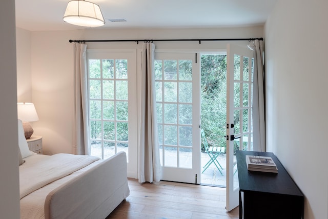 bedroom featuring multiple windows, hardwood / wood-style flooring, and access to exterior