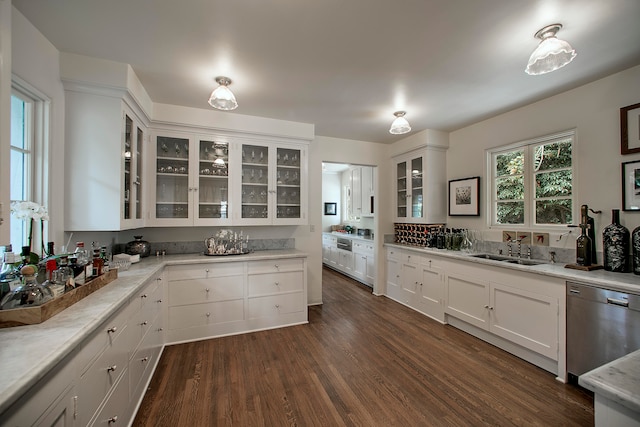 kitchen with stainless steel dishwasher, sink, white cabinetry, and dark wood-type flooring