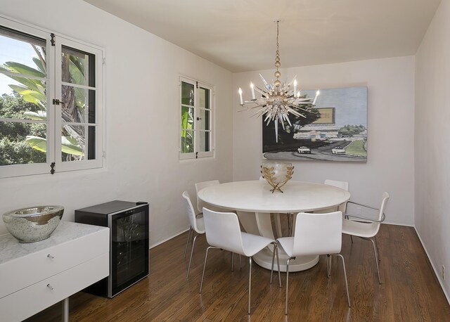 dining space featuring beverage cooler, a notable chandelier, and dark hardwood / wood-style floors