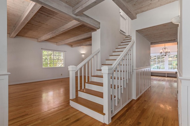 staircase featuring a chandelier, wood-type flooring, and wooden ceiling