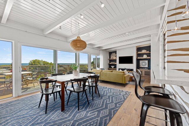 dining space with built in features, beam ceiling, hardwood / wood-style floors, and a healthy amount of sunlight