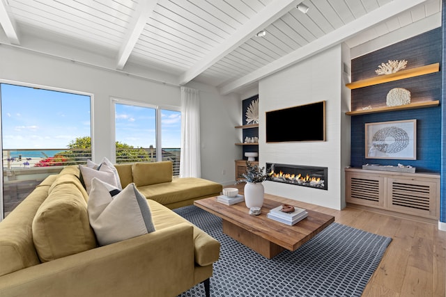 living room with a water view, wooden ceiling, beam ceiling, a large fireplace, and light hardwood / wood-style flooring