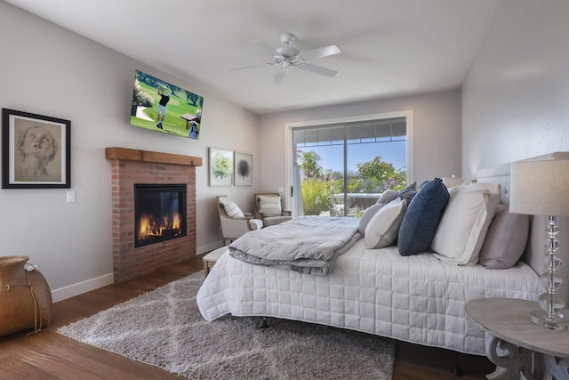 bedroom with ceiling fan, wood finished floors, baseboards, access to outside, and a brick fireplace