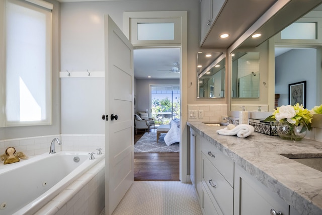 full bathroom featuring double vanity, a tub with jets, ensuite bathroom, tile patterned flooring, and a sink