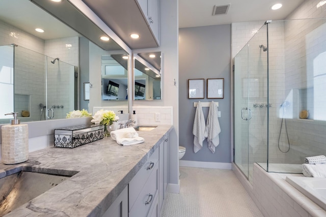 bathroom featuring toilet, a stall shower, double vanity, and visible vents