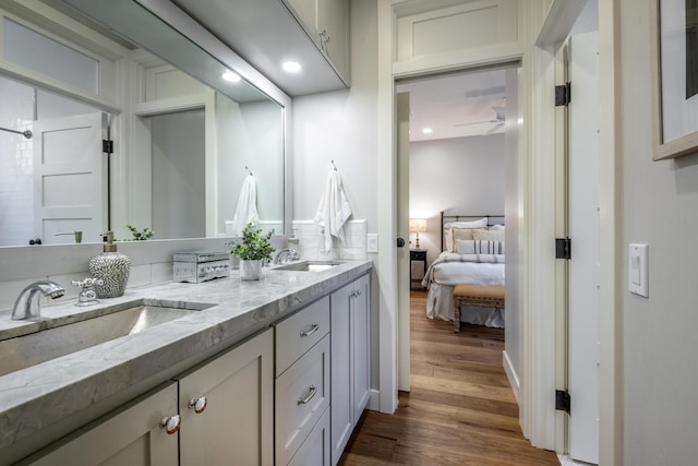 ensuite bathroom with double vanity, wood finished floors, a sink, and connected bathroom