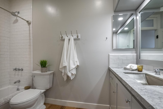 full bathroom with toilet, washtub / shower combination, vanity, wood finished floors, and baseboards