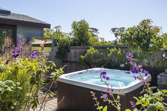 view of swimming pool featuring fence and a hot tub