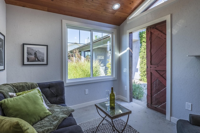 living area with a textured wall, lofted ceiling, and plenty of natural light