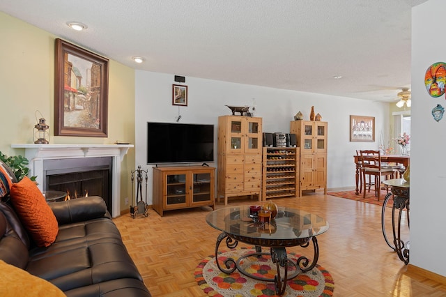 living room featuring a textured ceiling, ceiling fan, and light parquet flooring