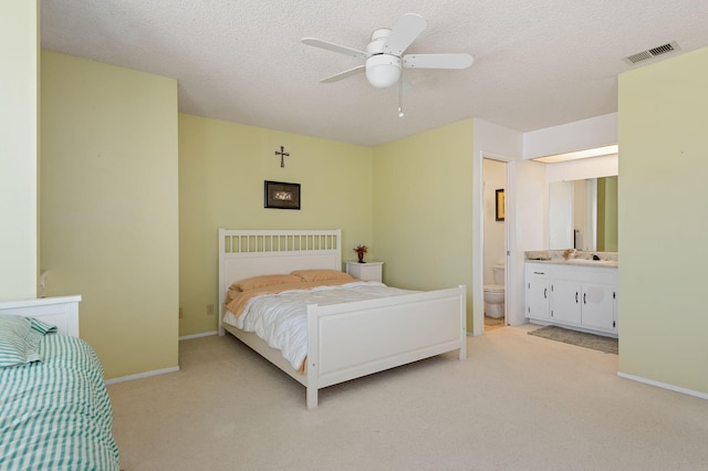 carpeted bedroom with a textured ceiling, ceiling fan, sink, and ensuite bathroom