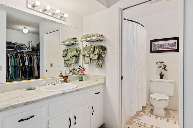 bathroom with tile patterned flooring, toilet, walk in shower, and vanity