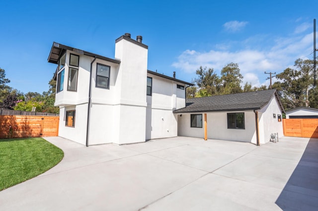 rear view of property with a patio and a lawn