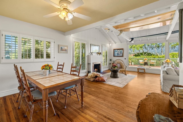 3050 Serena Rd, Santa Barbara, CA 93105 - dining space featuring a ceiling fan, wood finished floors, baseboards, a lit fireplace, and lofted ceiling with beams
