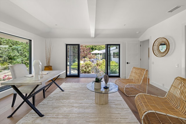 interior space featuring vaulted ceiling with beams and light hardwood / wood-style floors