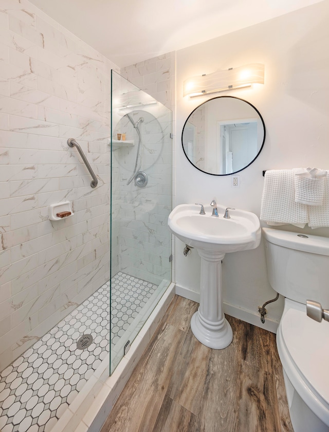 bathroom with a tile shower, hardwood / wood-style flooring, and toilet