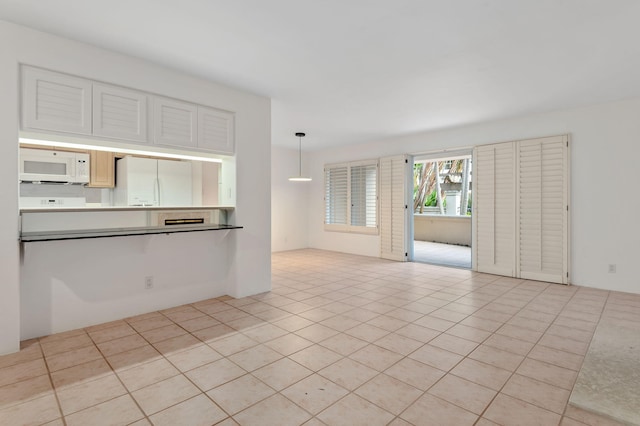 kitchen with white appliances, hanging light fixtures, and light tile patterned floors