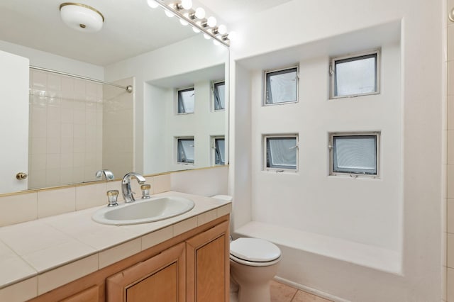 full bathroom featuring tiled shower / bath combo, vanity, toilet, and tile patterned floors