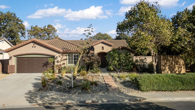 mediterranean / spanish house with stucco siding, driveway, fence, a garage, and a tiled roof