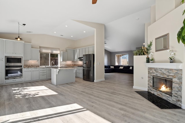 kitchen with light wood-type flooring, a sink, open floor plan, a center island, and stainless steel appliances